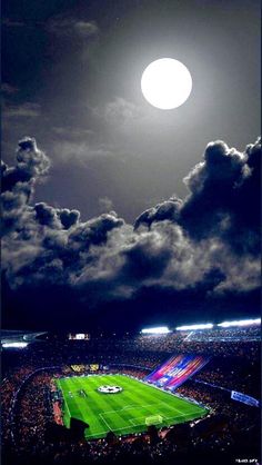 a full moon is seen above a soccer field in the dark night sky with clouds