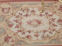 an antique rug with flowers and leaves on the border is hanging from a gold frame