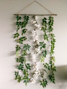 a wall hanging with white flowers and green leaves