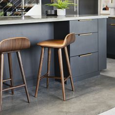 two wooden stools sitting next to each other in a kitchen with gray cabinets and counter tops