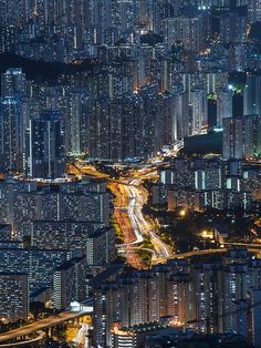 an aerial view of a city at night with lots of tall buildings in the background