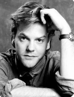 a black and white photo of a man with his hand on his head looking at the camera