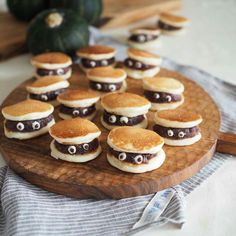 a wooden plate topped with mini hamburgers covered in frosting and googly eyes