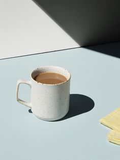 a cup of coffee sitting on top of a table next to a yellow towel and napkin