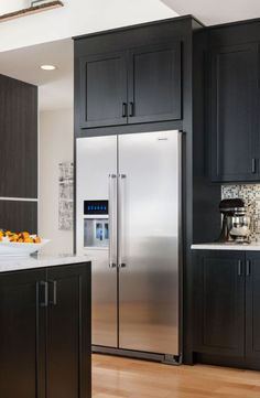 a stainless steel refrigerator in a kitchen next to black cupboards and counter top space