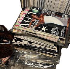 an open suitcase filled with magazines on top of plastic wrapper next to a pair of scissors