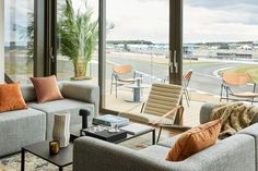 a living room filled with furniture next to a large glass window overlooking an airport runway