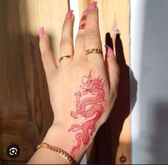 a woman's hand with a red dragon tattoo on her left wrist and fingers