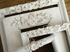 three white frames with flowers and leaves on them