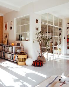 a living room filled with lots of furniture and bookshelves next to a window