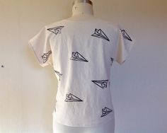 "Simple, boxy top made of 100% linen in white that has been block printed with a paper airplanes in black ink. Currently available in XS, S, M, L & XL Please choose size at checkout Size XS measures 37\" around the bust 38\" around the hem 21\" long Size Small measures 39\" around the bust 41\" around the hem 22\" from shoulder to hem Size Medium measures 42\" around the bust 44\" around the hem 23\" from shoulder to hem Size Large measures 45\" around the bust 47\" around the hem 25\" from White Hand Printed Crew Neck Top, White Hand Printed Short Sleeve Tops, White Printed Everyday Tops, White Printed Tops For Everyday, Everyday White Printed Tops, Casual White Hand-printed Top, Airplane Print, Boxy Top, Linen Tank Top