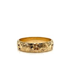 a gold wedding band with flowers on the side and leaves in the middle, against a white background