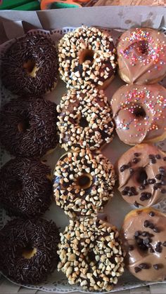 there are many different donuts in the box on the table and one has chocolate sprinkles