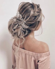 a woman with blonde hair in a messy updo is wearing an off the shoulder top