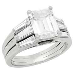 A simply outstanding diamond engagement ring from the Retro (ca1940) era by the famed maker Tiffany & Co.! This beautiful ring is made of platinum and holds a gorgeous Emerald Cut diamond at the center. The diamond, which is prong set, has I color and VS1 clarity and weighs approximately 3.03ct. Resting at the shoulders of the ring are six sparkling tapered baguette cut diamonds, which have I-J range color, VS2 clarity and a total weight of approximately 0.11ctw, tension set in three separate ba 1960s Engagement Ring, Tiffany Setting, Emerald Cut Diamond Engagement Ring, Tiffany Diamond, Emerald Cut Diamond Engagement, Contemporary Engagement Rings, Emerald Cut Diamond, Platinum Engagement Rings, Deco Engagement Ring