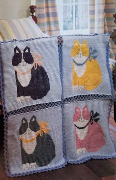 four pillows with cats on them are sitting on the floor in front of a window