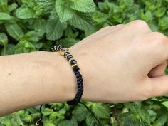 a person's arm with a black and gold beaded bracelet on it