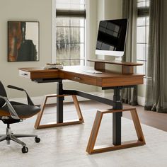 a computer desk with a monitor and keyboard on it in front of a large window