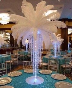 the table is set with white plates and silverware, which are accented with feathers