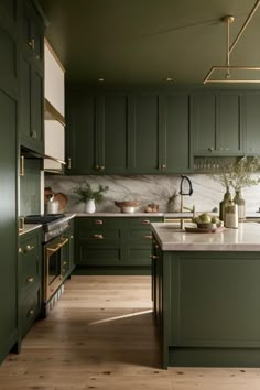 a kitchen with green cabinets and marble counter tops on the island in front of an oven