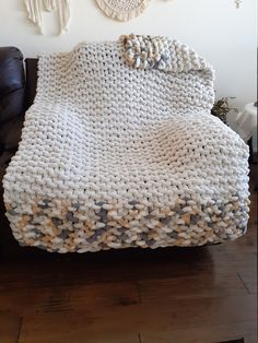 a white blanket sitting on top of a black leather couch next to a wall hanging