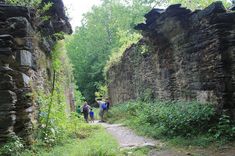 several people are walking down a path in an old, crumbling stone walled area