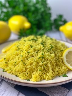 a white plate topped with yellow rice next to lemons