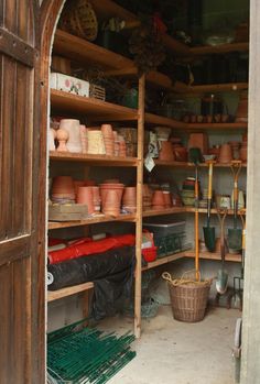 the inside of a potting shed with lots of pots on shelves and other items