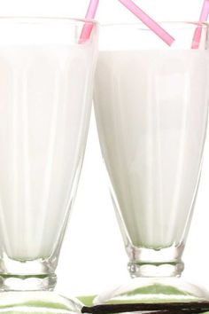 two glasses filled with milk and pink straws