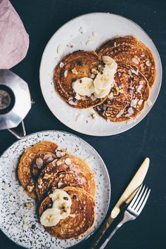 two white plates topped with pancakes covered in banana slices