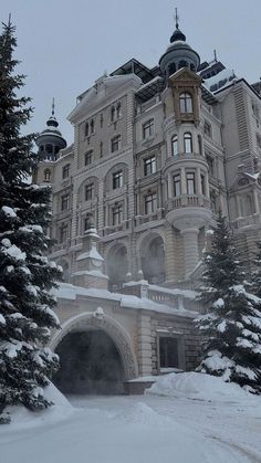 a large building with snow on the ground and trees around it in front of it