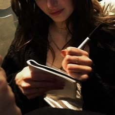 a woman holding a pen and writing on a piece of paper while sitting in a car