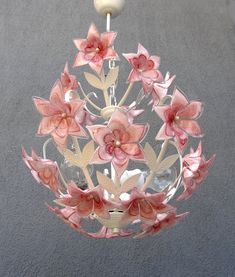 a glass chandelier with pink flowers hanging from it's sides and a white light fixture in the middle