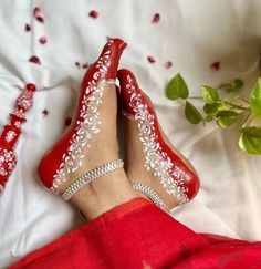 a woman's feet wearing red shoes with white lace on them and flowers in the background