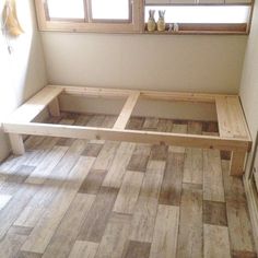 a wooden bench sitting on top of a hard wood floor next to a window in a room