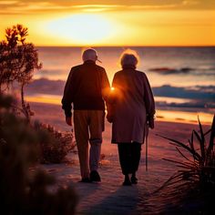 an older couple walking on the beach at sunset or sunrise with their back to the camera