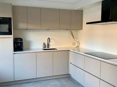 an empty kitchen with white cabinets and black appliances on the counter top, in front of a microwave oven