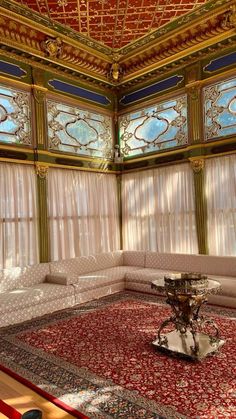 an ornately decorated living room with red carpet and white couches, windows, and rugs