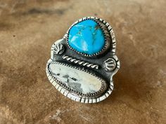 "This statement ring is truly one of a kind! Stunning Kingman Turquoise & White Buffalo are set together in rustic serrated sterling silver bezel settings. Each stone is surrounded by hand stamped details that have been accentuated by oxidation. The stones are grounded by textured fine silver shot (balls) & a simple twisted wire in the middle. Hand stamped lines grace the entire perimeter of the ring. Super comfy half round split shank band has been soldered to the back and set to a size 6. This cannot be resized. This ring has been brought to a rustic finish as well as polished to a high shine to add contrast. Ready to ship! Xo  *SIZE 6. Cannot be resized* MATERIALS: Sterling silver, sterling silver wire, fine silver, natural Turquoise (I made this awhile ago... unsure of the type) & natu Handmade Rustic Silver Turquoise Ring, Western Style Stamped Turquoise Ring Gift, Rustic Silver Turquoise Ring For Gift, Unique Stamped Turquoise Ring, Rustic Silver Turquoise Ring Gift, Artisan Stamped Turquoise Ring, Ear Hangers, Twisted Wire, Turquoise Cuff