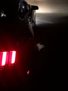 the tail lights of a sports car are glowing in the dark