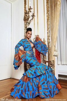 a woman in a blue and orange dress sitting on a chair with her arms outstretched