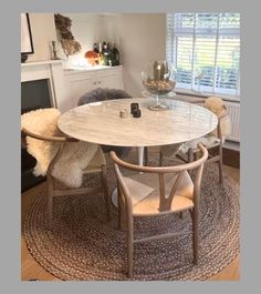 a dining room table with two chairs and a rug on the floor in front of it