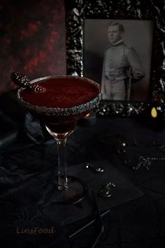 a red cocktail sitting on top of a table next to a black and white photo