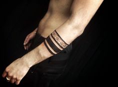 a man's bare foot with black lines on his arm and wristbands