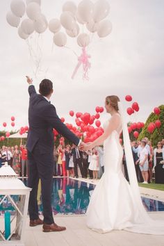 a bride and groom holding hands with balloons in the air