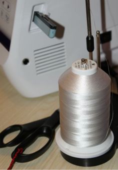 a spool of thread sitting on top of a table next to scissors and a sewing machine