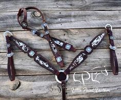 a brown and white horse bridle with matching reins on wooden planked floor