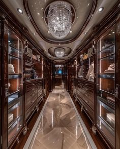 a large walk in closet filled with lots of glass shelves and lights hanging from the ceiling