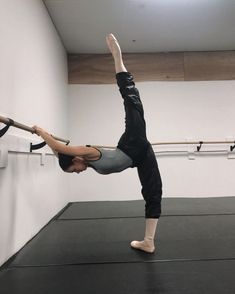 a woman doing a handstand with a pole in front of her on the floor