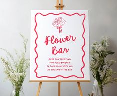 a flower bar sign sitting on an easel next to some vases with flowers